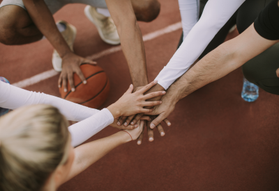 Sportler auf der Leichtathletikbahn legen Hände zusammen