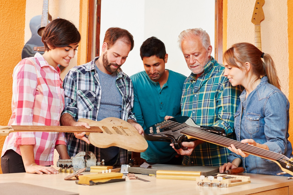 Quatre jeunes gens et leur formateur dans un atelier de luthier