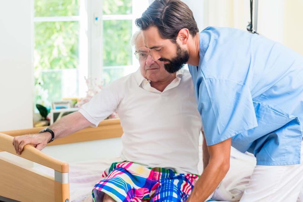 Un infirmier aide un homme âgé à passer du fauteuil roulant au lit