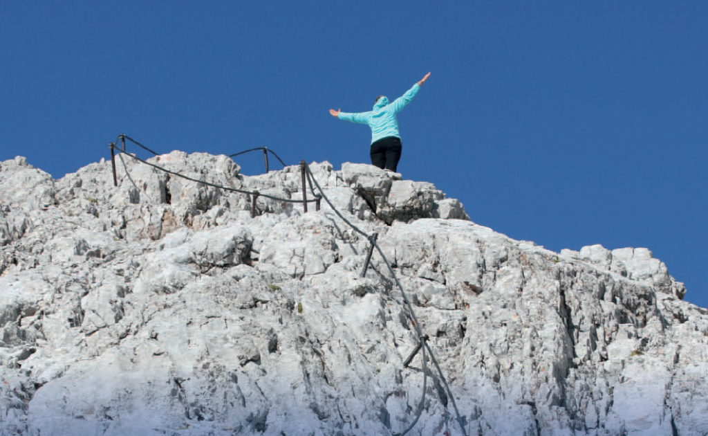 Femme debout sur le sommet d'une montagne avec les bras ouverts