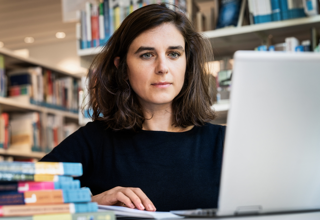 Femme dans une bibliothèque devant un ordinateur portable