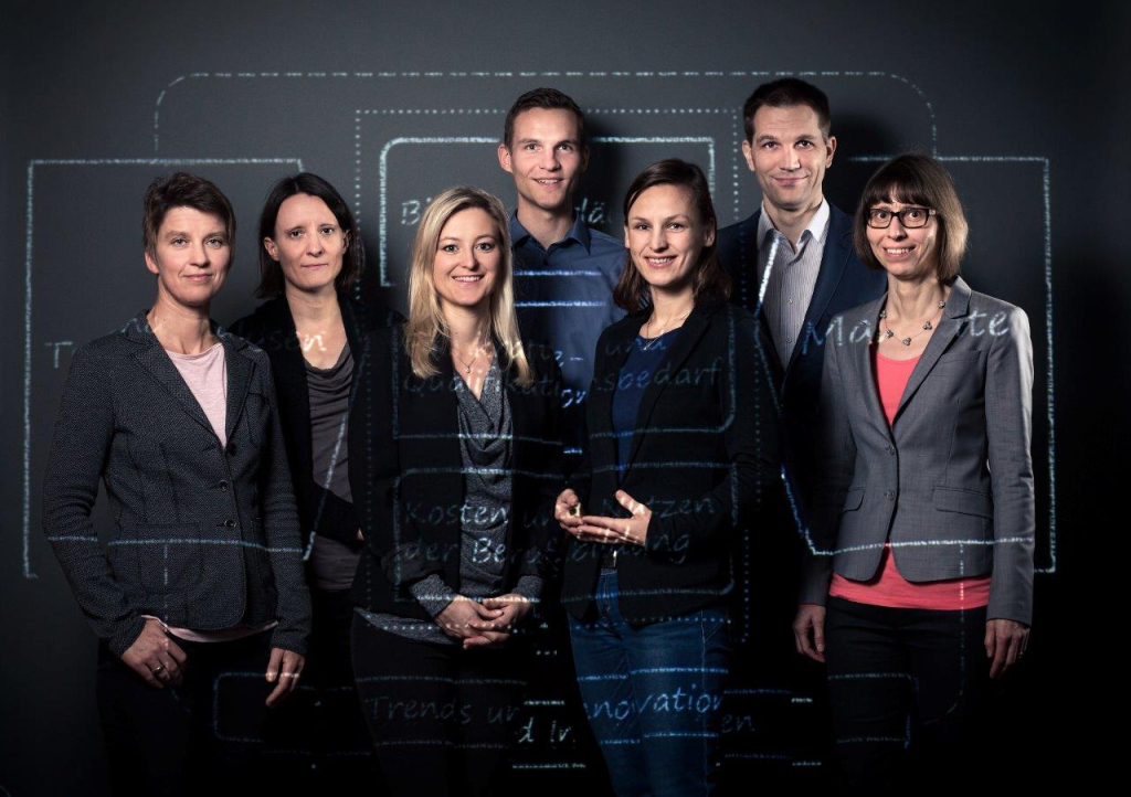 Portrait de l'équipe de recherche de l'Observatoire suisse pour la formation professionnelle devant le schéma de leur activités de recherche